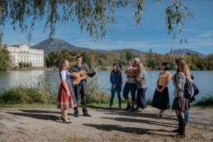 Dana Hammett and Dmitry Iogman enchant an audience with a live lakeside performance of classic tunes from a renowned family musical, set against the historic backdrop of Schloss Leopoldskron.