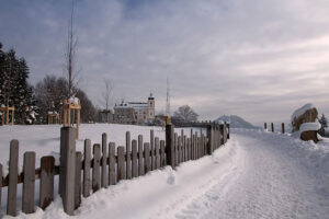 Distant right-side view of Maria Plain pilgrimage church in winter, surrounded by snow.