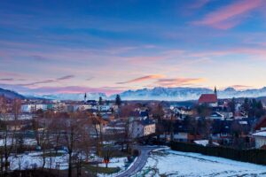 Oberndorf in winter, covered in snow with the Alpine mountains in the background.