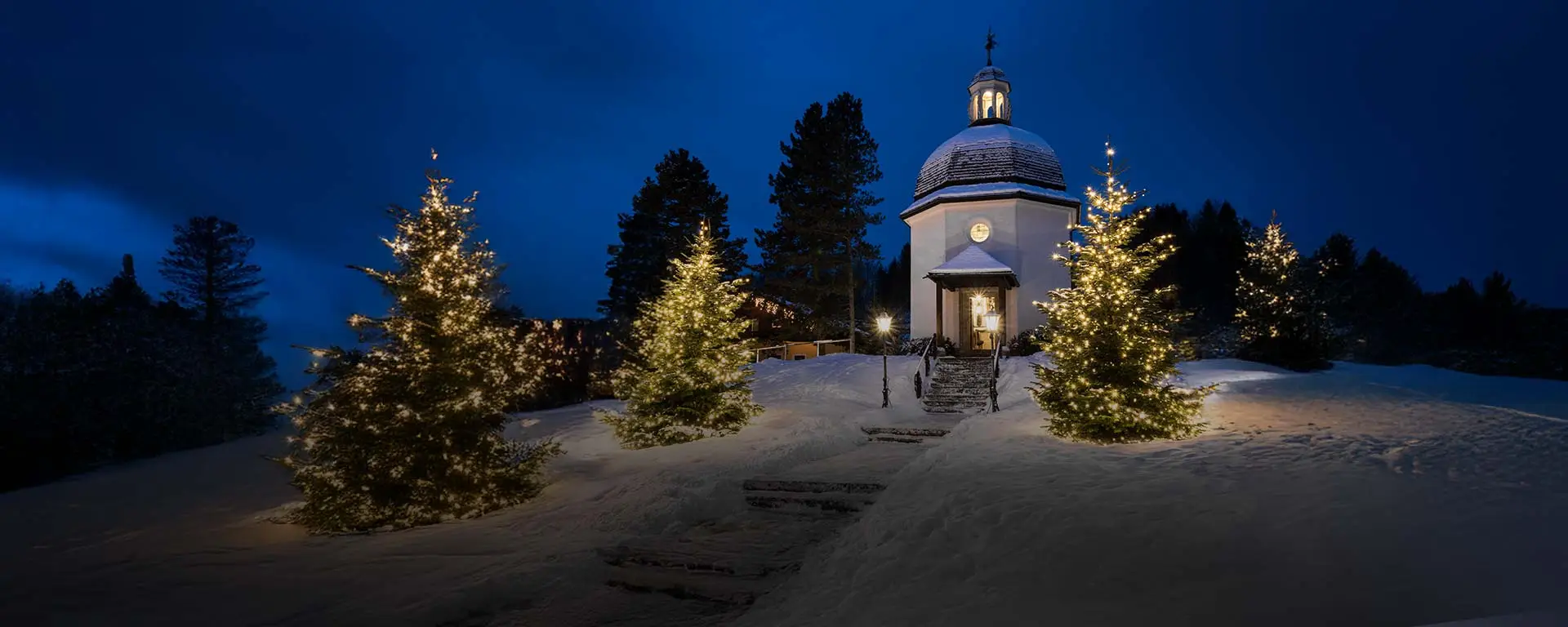 Silent Night Chapel by night in Oberndorf, Austria, softly illuminated under a starlit winter sky.