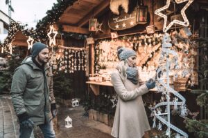 Couple enjoying St. Wolfgang Christmas Market, surrounded by festive stalls and holiday lights.