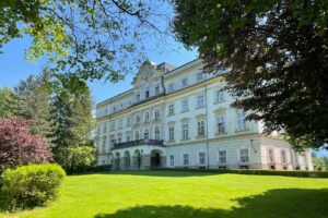 A pristine view of Schloss Leopoldskron, the majestic rococo mansion, set against clear skies and surrounded by lush gardens, recognized as the cinematic stand-in for an iconic family villa in a legendary musical film.