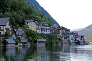 Historic buildings of Hallstatt viewed from the water, with traditional wooden architecture and alpine mountains in the background.