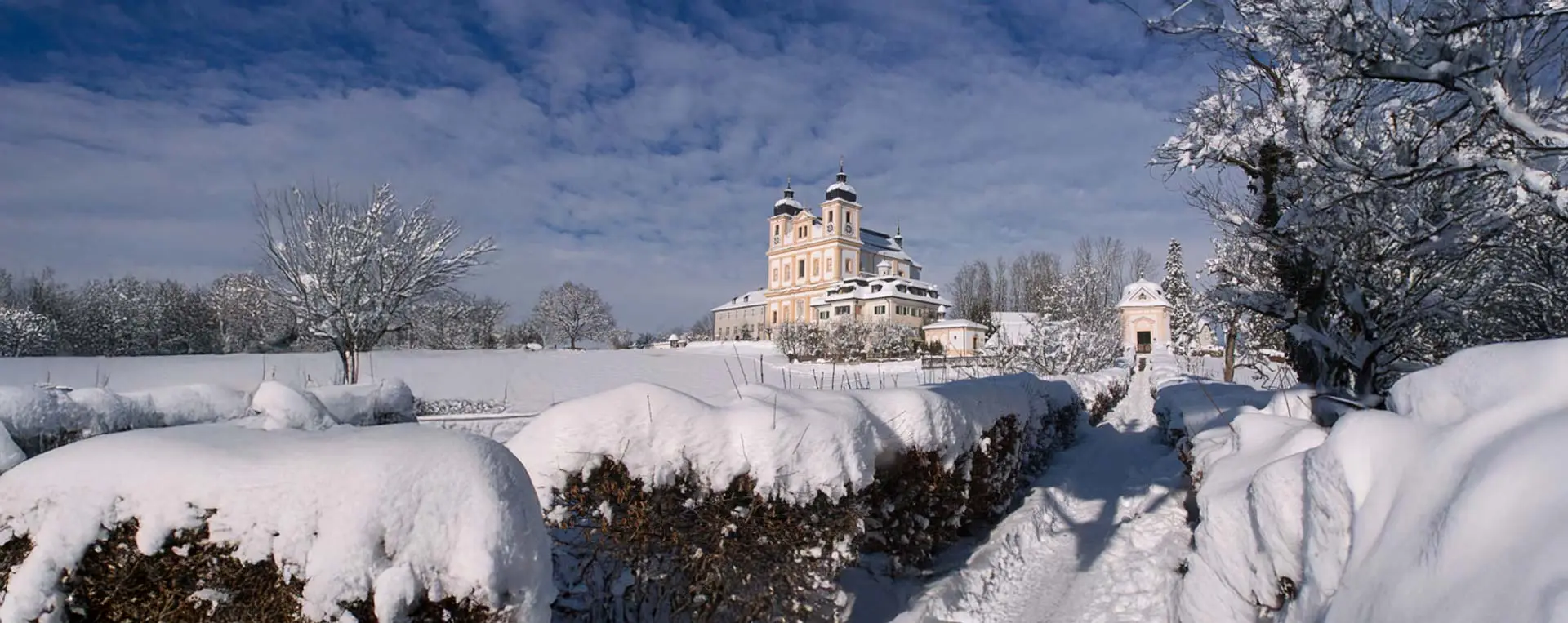 Maria Plain pilgrimage church in winter, surrounded by a snowy landscape.