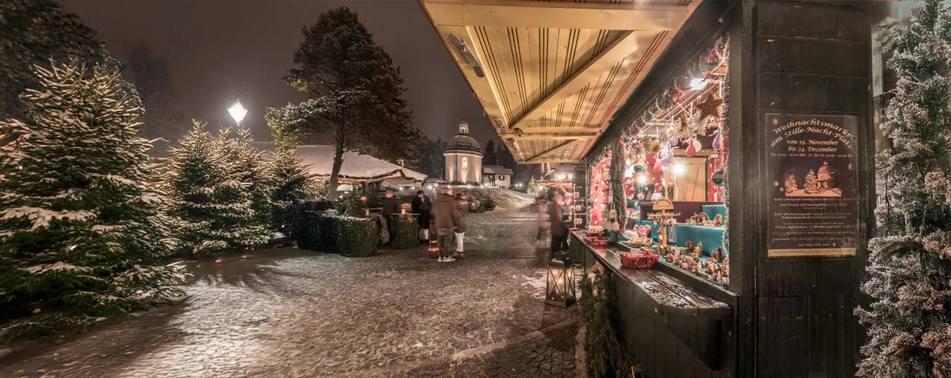 Christmas market in Oberndorf, with festive stalls in front of the illuminated Silent Night Chapel.