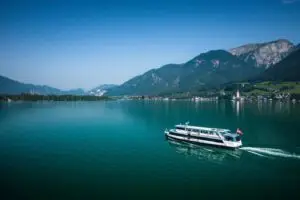 A ship sailing on Wolfgangsee in summer, surrounded by blue water and mountains in the background.