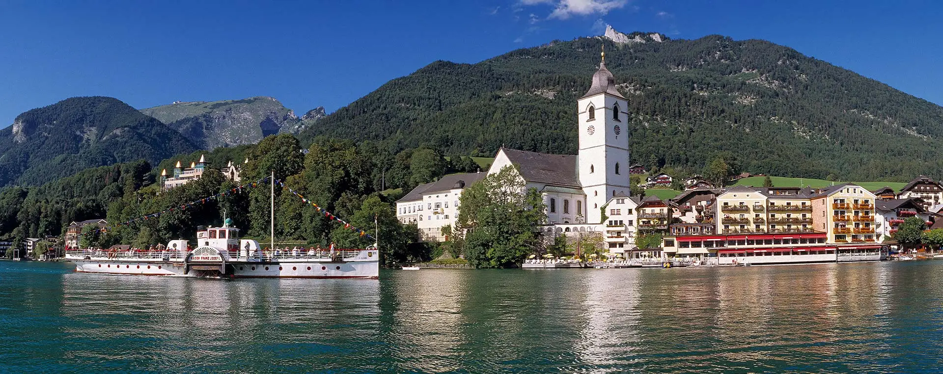 A view of St. Wolfgang with its charming village and alpine backdrop, highlighting the boat ride from Strobl to St. Gilgen.