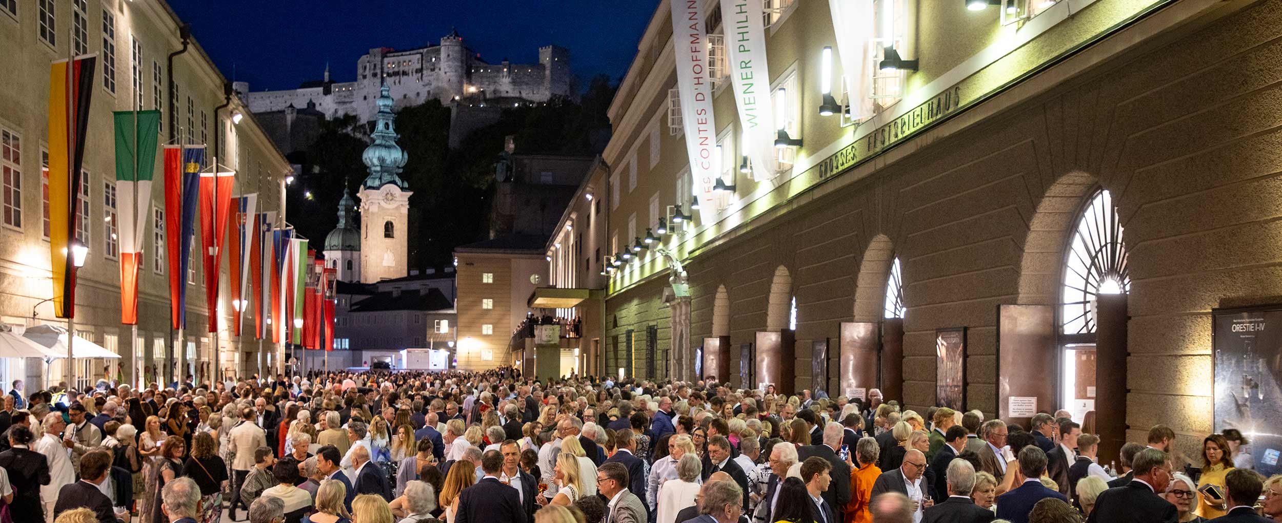 Salzburg Festival Hall – Travel Award Highlight Crowds in front of Salzburg Festival Hall during summer evening with Hohensalzburg Fortress in background – Salzburg No. 1 Lonely Planet